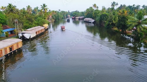 Shikkara tourism , Kumarakam world tourism spot ,Aerial view of Kerala's backwaters with rows of houseboats lined up and a small boat sailing through the water nearby photo