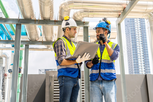 Obraz na plátne Collaboration, Two young construction workers discuss plans while reviewing blueprints on a rooftop