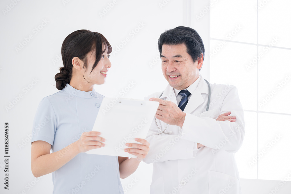 A smiling nurse talking to a doctor over a medical record Image of a patient signing off or treatment plan