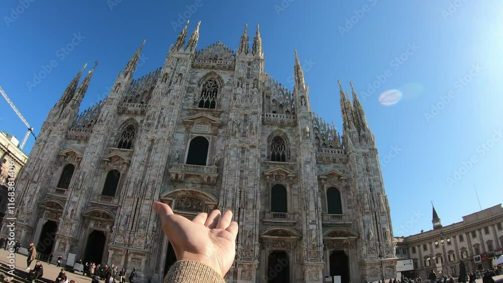 Woman taking photo in front of Milan Cathedral . She is wearing a red sweater and she is looking up at the sky