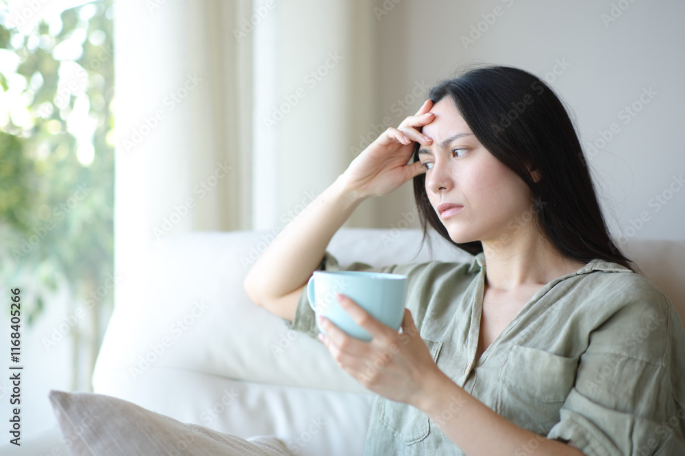 Worried asian woman drinking coffee at home Worried asian woman drinking coffee at home