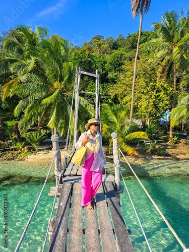 Strolling across a rustic bridge in the tranquil paradise of Koh Kood Thailand photo