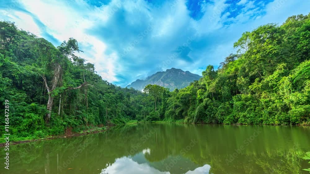 Time lapse Reflection of Doi Luang Chiang Dao in a lake reflecting lush green trees under a vibrant blue sky with white clouds. A tranquil setting showcasing unspoiled nature and tropical wilderness Time lapse Reflection of Doi Luang Chiang Dao in a lake reflecting lush green trees under a vibrant blue sky with white clouds. A tranquil setting showcasing unspoiled nature and tropical wilderness