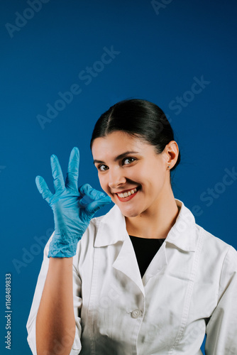 Pediatric doctor in white coat with stethoscope and blue gloves smiling on blue background