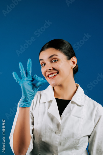 Portrait of a woman pediatric doctor in a white coat with a stethoscope on a blue background showcasing a friendly gesture