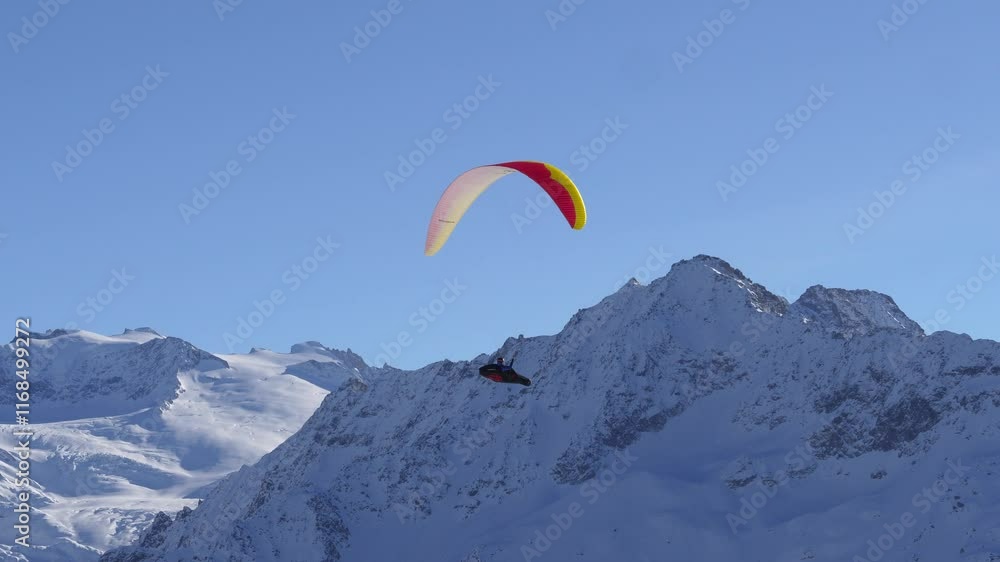paragliding in a beautiful winter landscape. The paraglider flies over the mountain peaks and enjoys the beautiful view with lots of snow. paragliding in a beautiful winter landscape. The paraglider flies over the mountain peaks and enjoys the beautiful view with lots of snow.