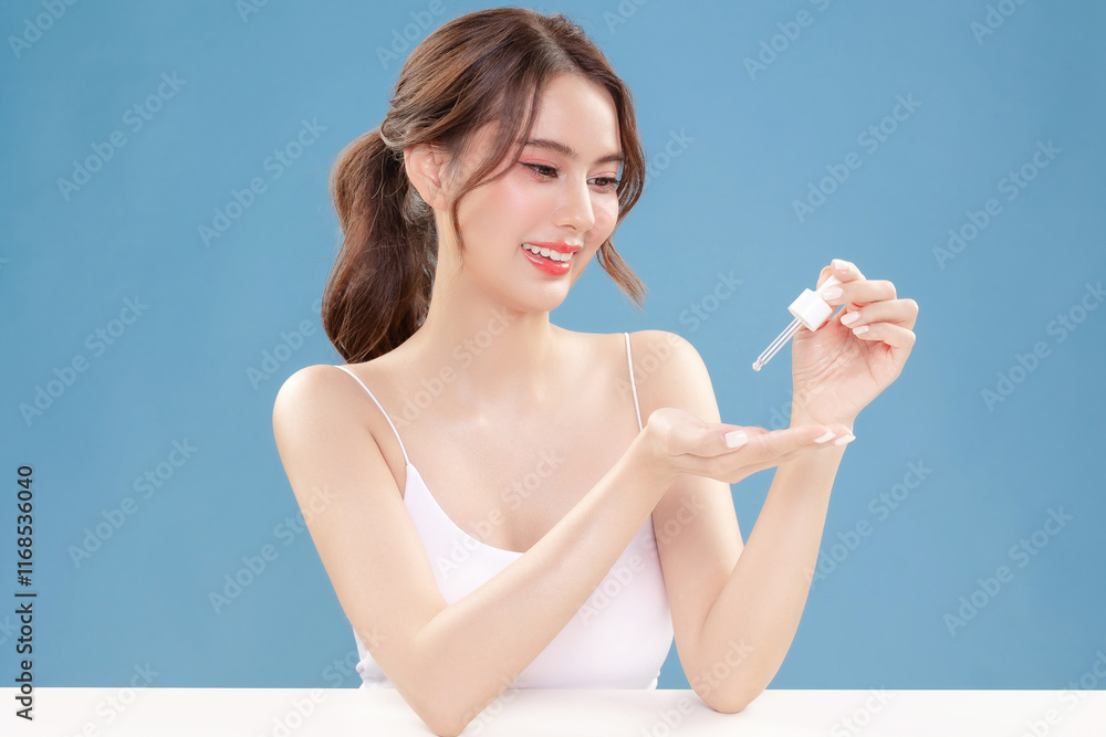 Young Asian beauty woman pull back hair with Koreans makeup style on face and perfect clean skin apply serum on isolated blue background. Facial treatment, Cosmetology, plastic surgery. Young Asian beauty woman pull back hair with Koreans makeup style on face and perfect clean skin apply serum on isolated blue background. Facial treatment, Cosmetology, plastic surgery.