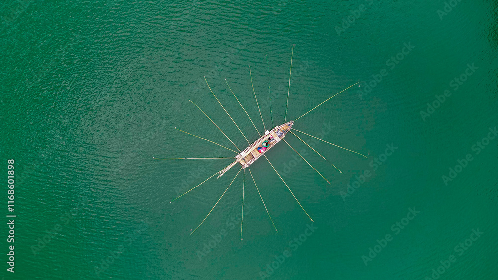 A fisherman balances on a small boat in the middle of a tranquil lake, managing multiple fishing rods as the calm waters reflect the serene surroundings. A fisherman balances on a small boat in the middle of a tranquil lake, managing multiple fishing rods as the calm waters reflect the serene surroundings.