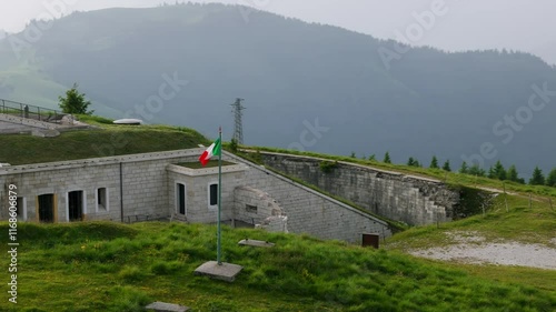 Forte Lisser, military fortress, Italian flag, Enego, Vicenza in Italy. Aerial drone orbiting photo