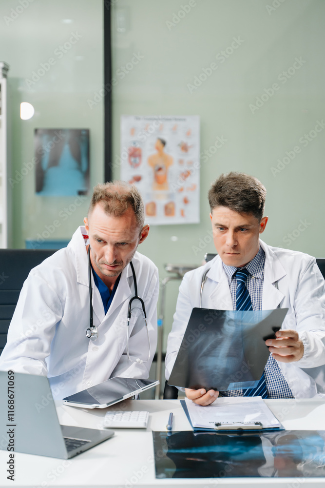© Nuttapong punna - Doctors analyzing an X-ray, collaborating with digital tools in a medical office. Showcasing teamwork, diagnostic
