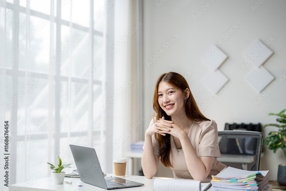 A woman is sitting at a desk with a laptop and a stack of papers A woman is sitting at a desk with a laptop and a stack of papers