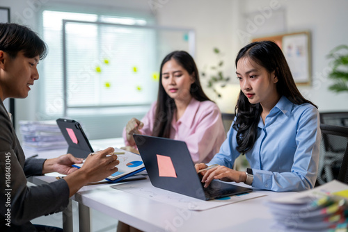 Three women are sitting at a table with laptops  one of them typing