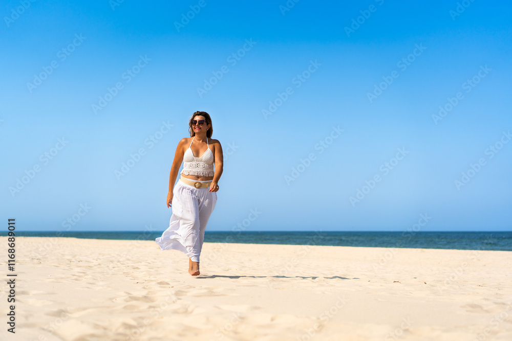Summertime by sea. Beautiful middle-aged woman walking on sandy beach on sunny summer day. Front view Summertime by sea. Beautiful middle-aged woman walking on sandy beach on sunny summer day. Front view