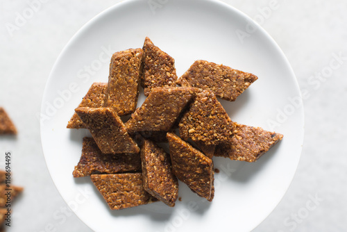 Overhead view of groundnut cake on a white plate, top view of nkatie cake or peanut cake on a plate, candy bar made with roasted peanuts and sugar photo