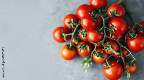 A vibrant cluster of ripe red cherry tomatoes on the vine, showcasing their natural freshness and color against a neutral gray background.