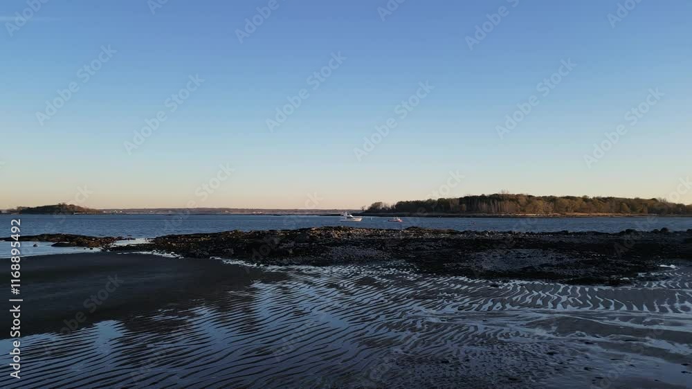 A tranquil coastal view during low tide featuring rippling sand, rocky shoreline, and clear blue sky. Ideal for nature, travel, and relaxation projects. A tranquil coastal view during low tide featuring rippling sand, rocky shoreline, and clear blue sky. Ideal for nature, travel, and relaxation projects.
