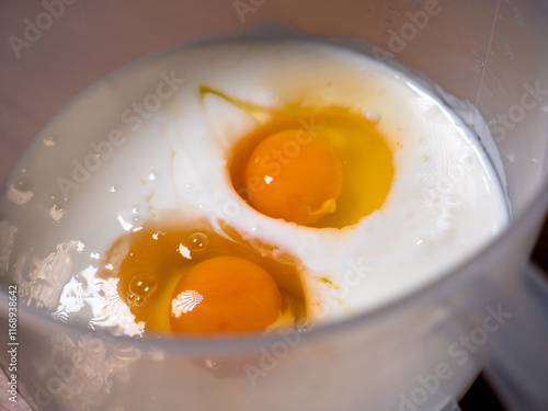Obraz na płótnie A bowl with yoghurt, two chicken eggs, and other ingredients ready to be mixed and prepare pancake batter w salonie