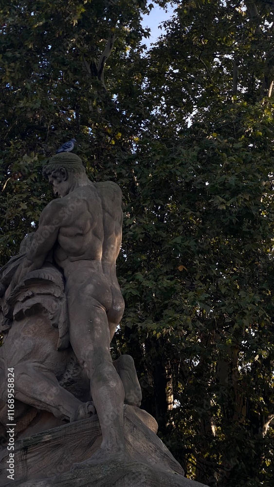 Naklejka premium Sculpture surrounded by greenery in a park.