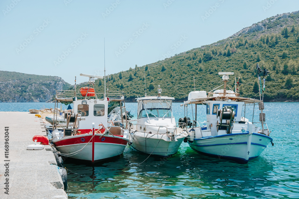 Three boats are docked at a pier, with one of them being a small red boat Three boats are docked at a pier, with one of them being a small red boat