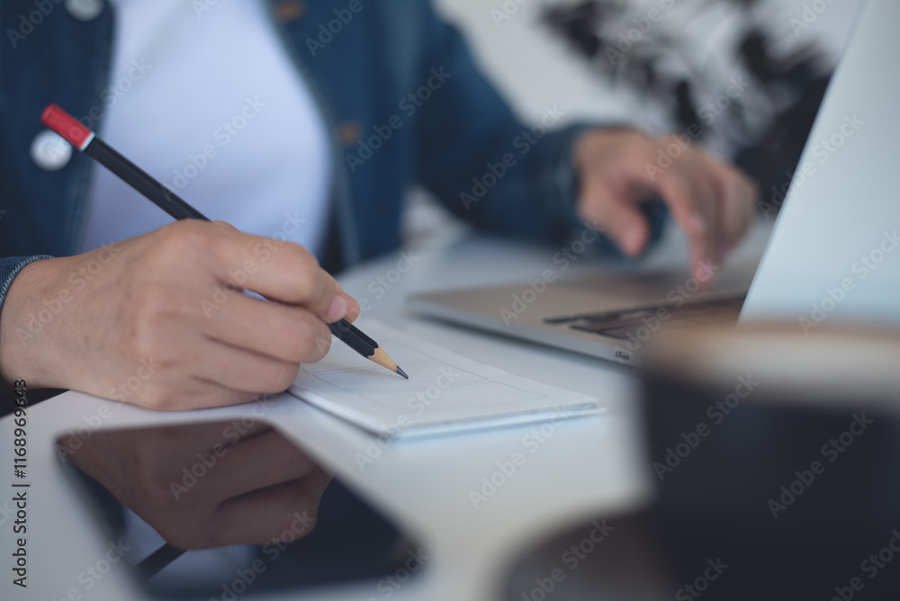 Fototapeta premium Close up, business woman hand writing on notepad, working on laptop computer at coffee shop. Woman planning work project. Student online study and taking note, e-learning concept