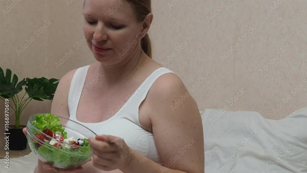 Pregnancy healthy food and people concept. future mom eating healthy salad and take care. Pregnant Woman Holding Bowl With Fresh Vegetable Salat While Sitting On Bed, Expectant Mother Enjoying Healthy