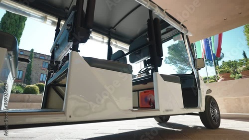 Luxury delivering service of expensive hotels, white golf cart waiting for guests on parking lot near the hotel, concept of luxury tourists or guests delivery service