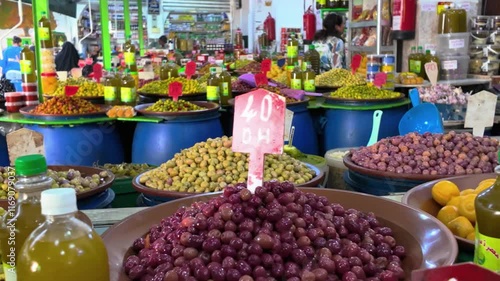 a vibrant display of seasoned chickpeas and olives, garnished with herbs, likely at a market or food stall. The colorful presentation and variety of ingredient