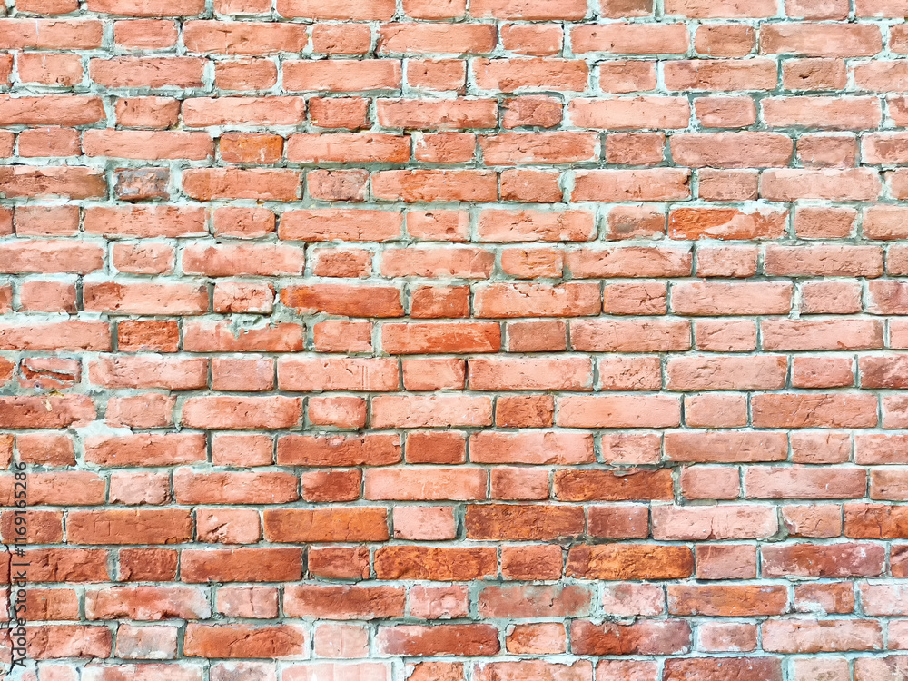 The rustic red brick wall displays variations in texture and color, reflecting natural light beautifully The rustic red brick wall displays variations in texture and color, reflecting natural light beautifully