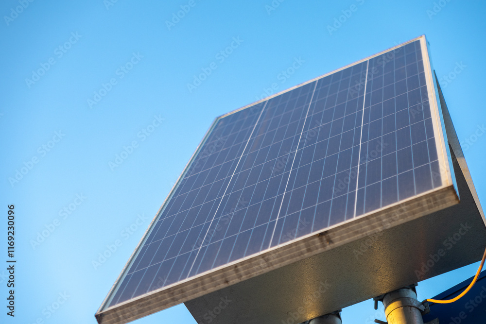 Obraz premium solar panel against a clear blue sky, mounted on a metal structure, capturing sunlight for renewable energy generation