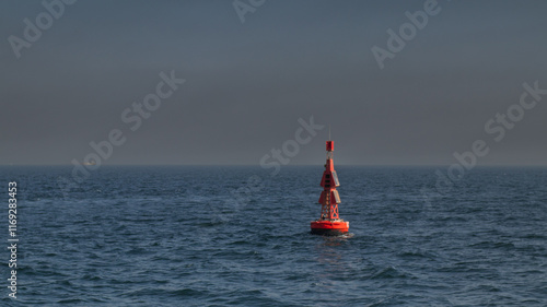 Obraz na płótnie Red buoy floating in the ocean close to coast. Navigating beacon in the sea for ships and other vessels w salonie