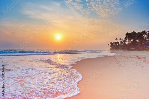 Colorful sunset viewed from the sea beach with soft waves and palm trees. Sri Lanka