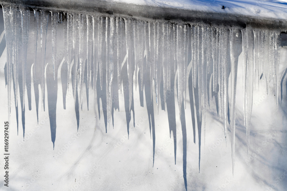 Icicles forming and melting on rooftop edge during winter thaw, seasonal freeze-thaw cycle. Risk for pedestrians in winter season. Icicle on rooftop of the building. Icicles hanging from the roof Icicles forming and melting on rooftop edge during winter thaw, seasonal freeze-thaw cycle. Risk for pedestrians in winter season. Icicle on rooftop of the building. Icicles hanging from the roof
