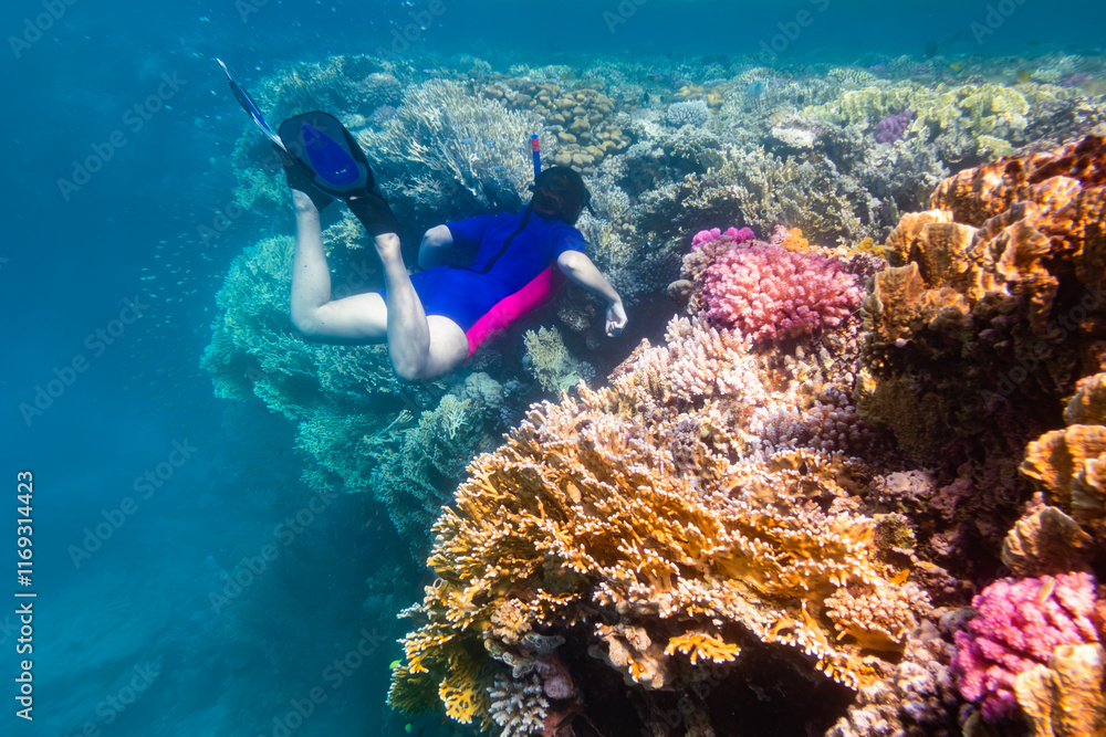 Woman snorkeling in clear water over vivid coral reef
