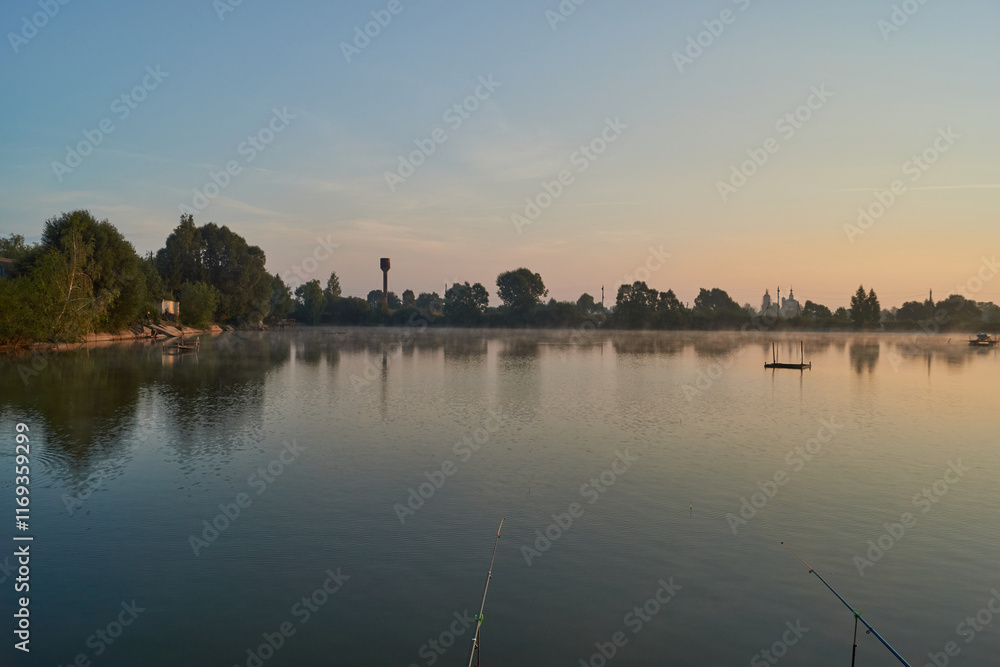 Fototapeta premium Sunrise over the lake. Fishing on the lake. Reflection in water.