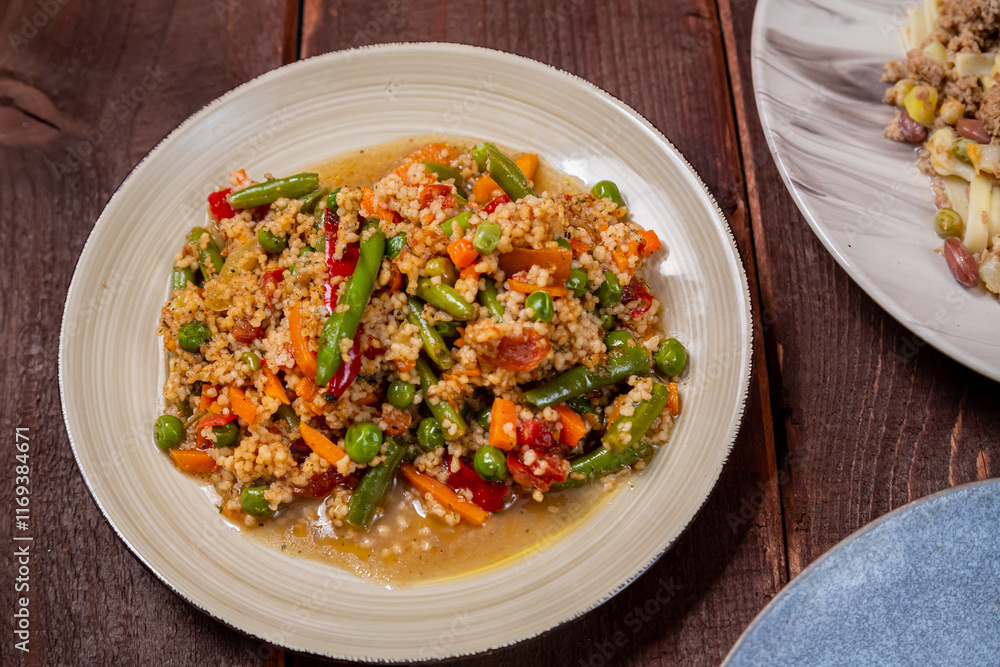 Couscous with vegetables in spices in a plate on a wooden table Couscous with vegetables in spices in a plate on a wooden table