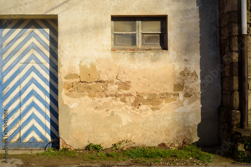 Puerta vieja de tablones de madera en diagonal pintados a rayas blancas y azules photo