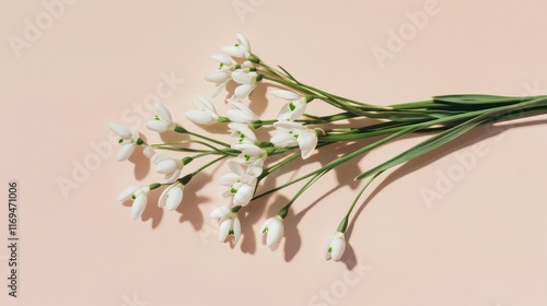 Elegant bouquet of snowdrop flowers arranged on a soft pink background