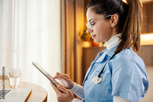 Valokuva Profile of female doctor sitting at home with tablet in hands and educating herself