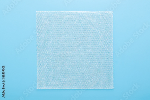 White transparent plastic air bubble film on light blue table background. Pastel color. Closeup. Material for fragile products packaging. Top down view. photo