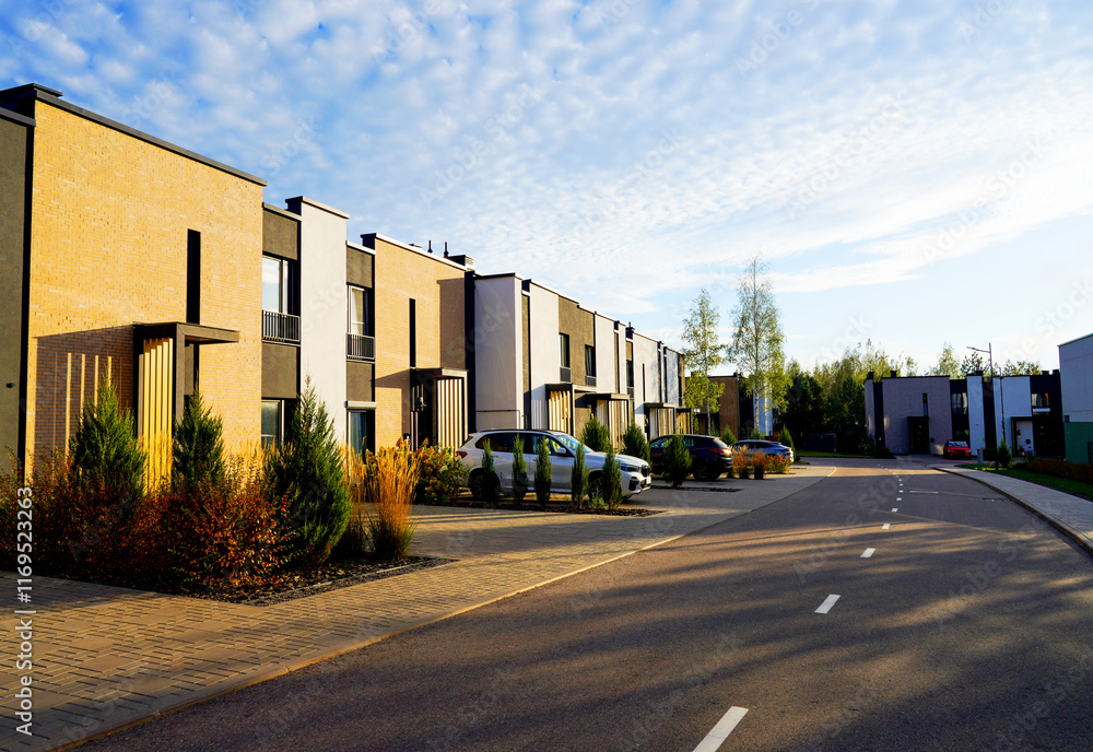 Townhouse in residential district. New apartment buildings in green enviroment. Street with Townhouse along asphalt road in gated community. Car on parking at house. Modern Townhouses in suburban. Townhouse in residential district. New apartment buildings in green enviroment. Street with Townhouse along asphalt road in gated community. Car on parking at house. Modern Townhouses in suburban.