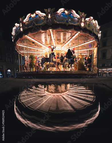 Nighttime view of a vintage carousel in Florence, Italy, illuminated with warm lights, featuring intricate horse designs and a clear reflection on water. photo