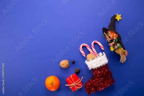 Epiphany day tradition. Befana and red stocking with sweet coal and candy on dark blue background. 