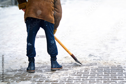 Worker breaking ice on sidewalk using an ice chopper, preventing injuries during winter season with proper tools for effective cleaning. Man remove ice and snow with hand ice chopper. Selective focus