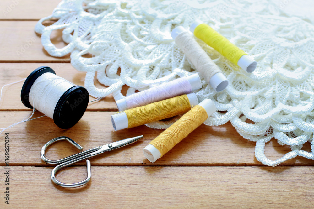 Colorful threads and beautiful white french lace on wooden table.