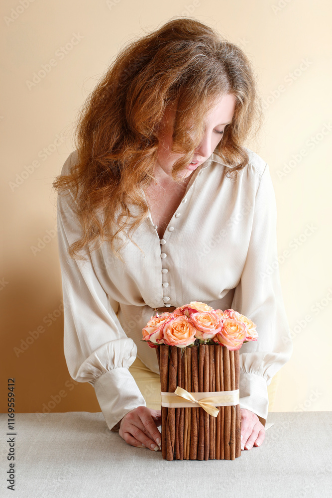 Woman is arranging rose flowers and candle holders on the table. Autumn home decoration ideas.