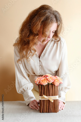 Obraz na płótnie Woman is arranging rose flowers and candle holders on the table. Autumn home decoration ideas. w salonie