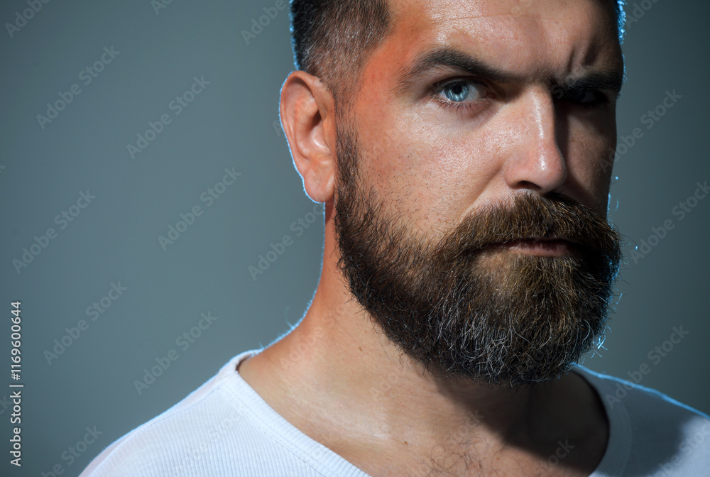 Obraz premium Man portrait. Handsome bearded man, closeup portrait. Serious man with beard and mustache in casual clothes. Confident pensive male after barbershop service. Fashionable unshaven man in white t-shirt.
