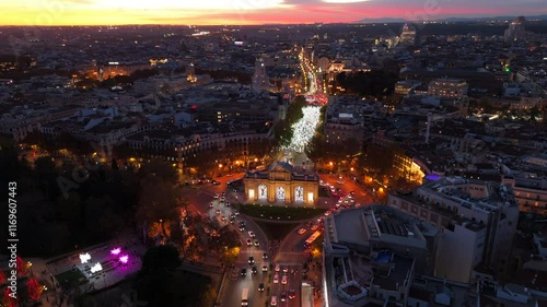 Impressive aerial drone shot beautifully captures iconic Puerta de Alcala in Madrid, breathtaking and vibrant cityscape as the sun sets, highlighting the charming area at dusk, heavy traffic. Spain