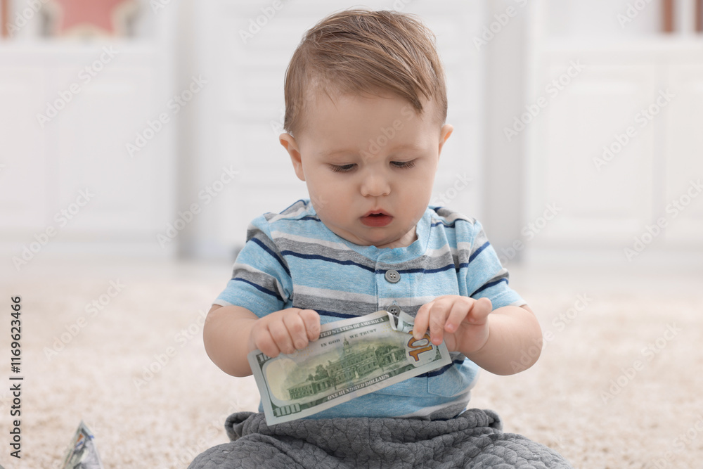 Little baby with dollar banknote on floor at home Little baby with dollar banknote on floor at home