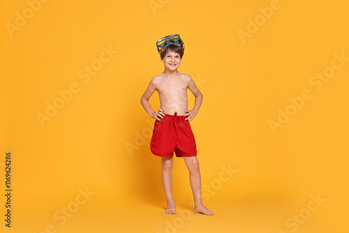 Little boy in beachwear with diving mask on orange background photo